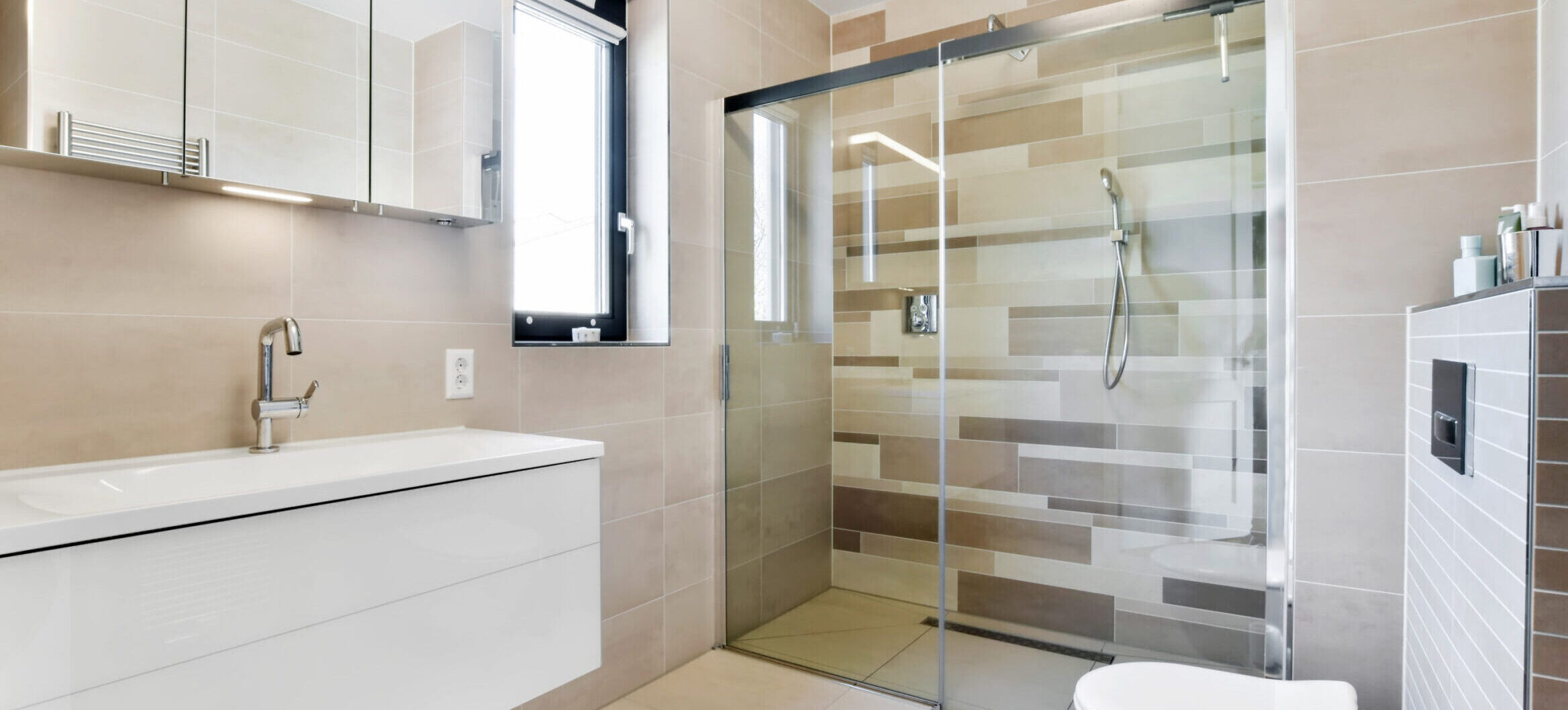 Modernized bathroom with a glass shower and unusual multi-colored tiles on the walls